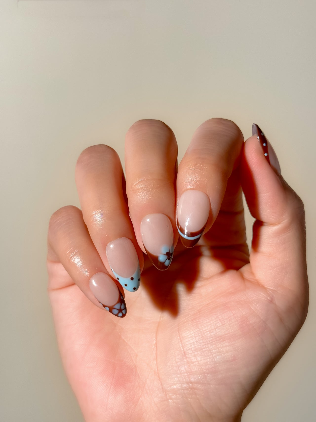 Brown and baby blue French tip press-on nails with retro floral detailing in a short almond shape. Handmade reusable false nails inspired by vintage 70s nail art, soft mod colour palettes and playful minimalist French manicure styles.