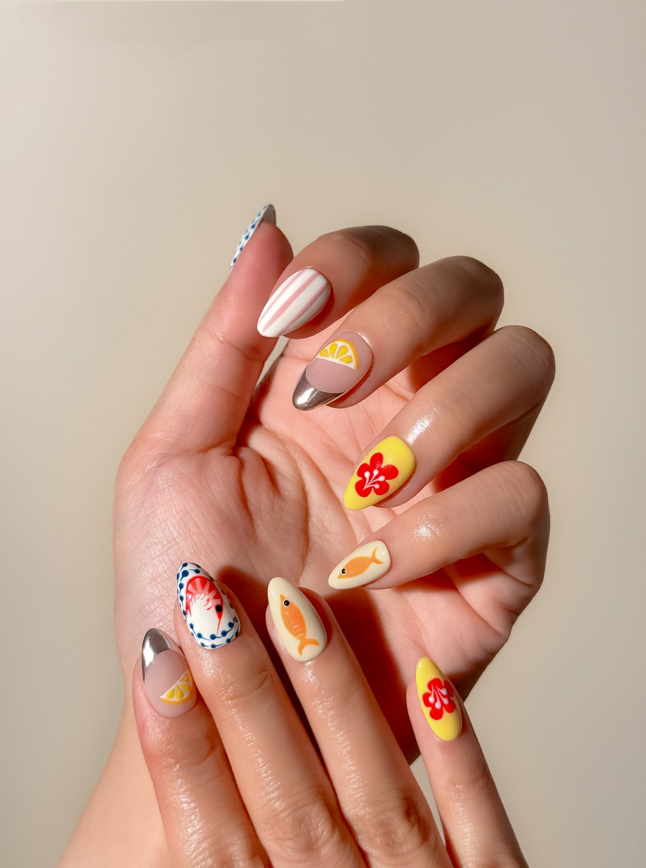 Colourful Mediterranean-inspired press-on nails with hand-painted fish, lemon and floral detailing in a medium almond shape. Handmade reusable false nails inspired by Italian summer holidays, Amalfi Coast aesthetics and playful European resort nail art.