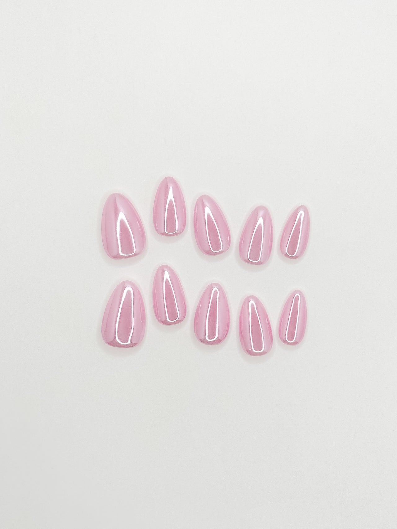 Glossy pink glazed press-on nails in a short almond shape with a translucent candy pink finish. Handmade reusable false nails inspired by glazed donut nails, clean girl manicures and soft glossy pink nail trends.