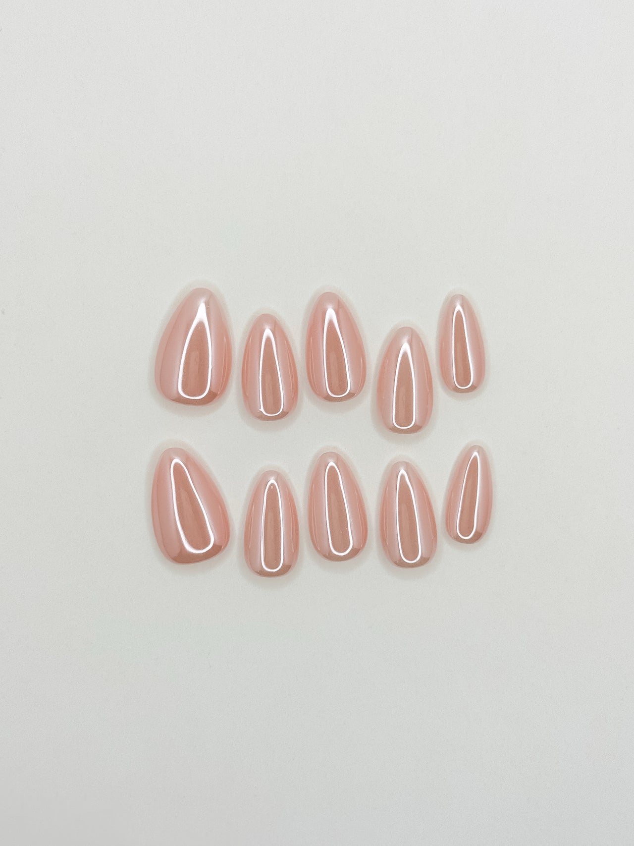 Glossy milky blush nude short almond press-on nails with a soft glazed finish photographed in natural sunlight.