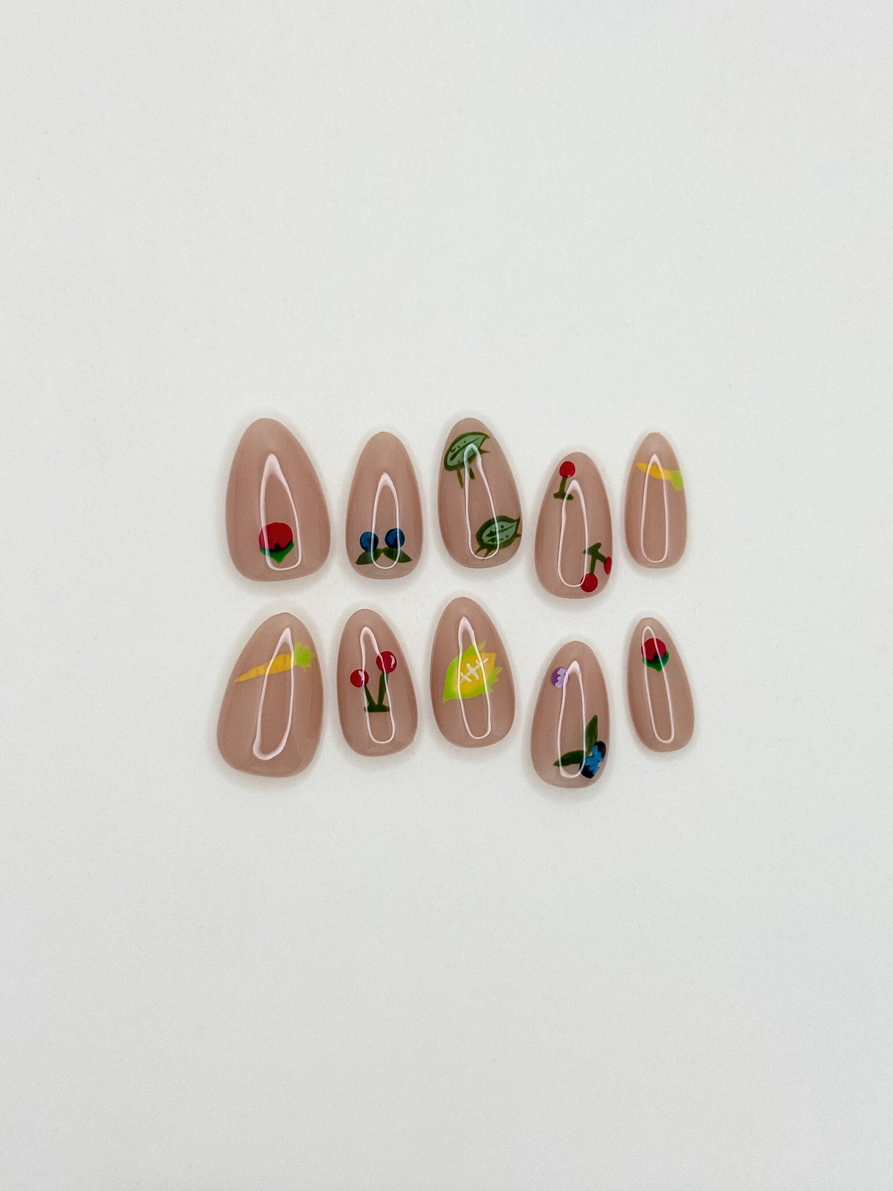 Summer Apron handmade short almond press-on nail set arranged on white, with a glossy nude base and colourful fruit, vegetable, flower and garden-bug illustrations