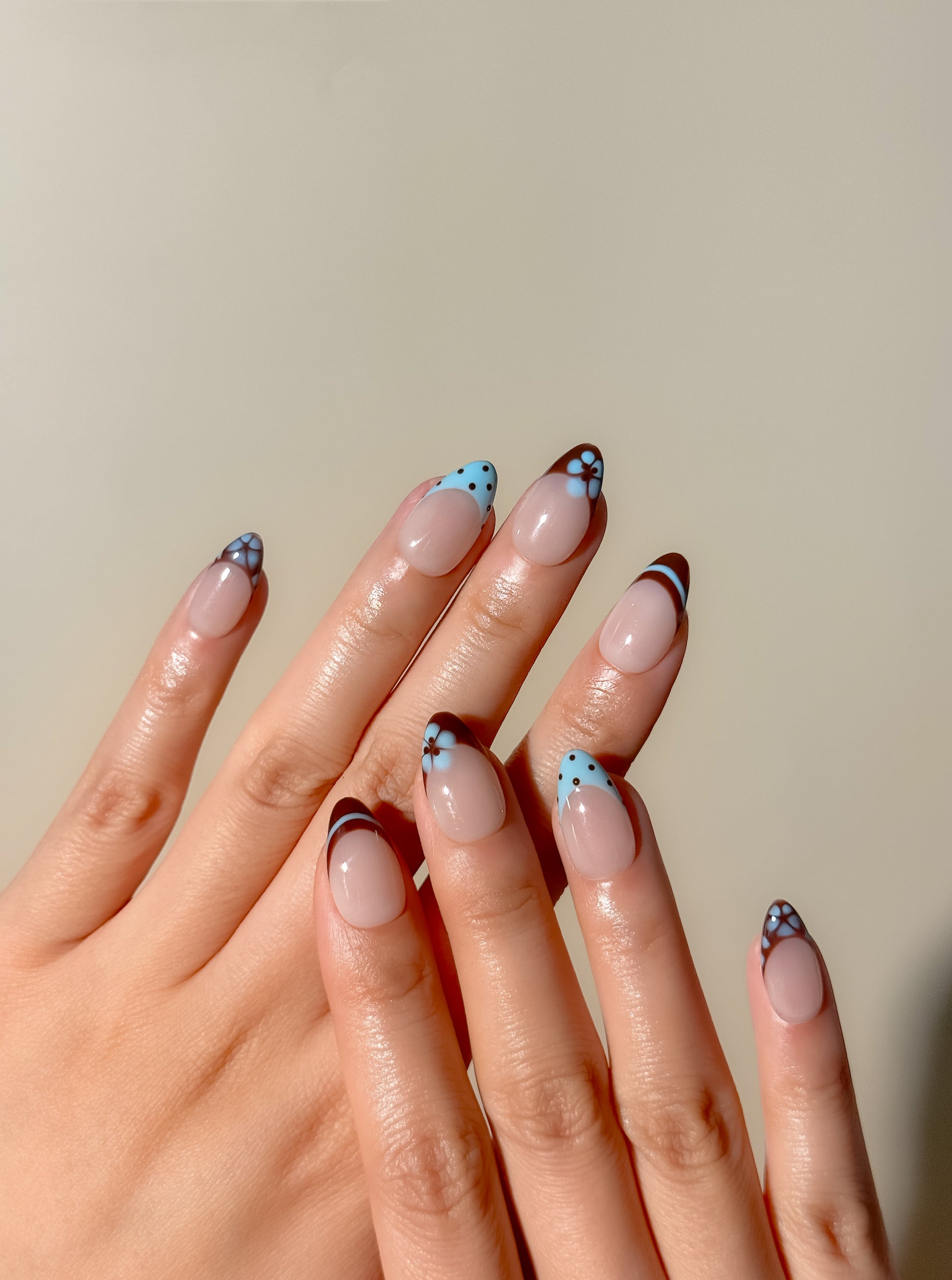 Brown and baby blue French tip press-on nails with retro floral detailing in a short almond shape. Handmade reusable false nails inspired by vintage 70s nail art, soft mod colour palettes and playful minimalist French manicure styles.