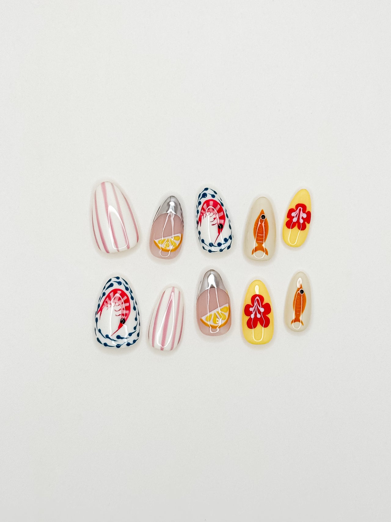 Colourful Mediterranean-inspired press-on nails with hand-painted fish, lemon and floral detailing in a medium almond shape. Handmade reusable false nails inspired by Italian summer holidays, Amalfi Coast aesthetics and playful European resort nail art.