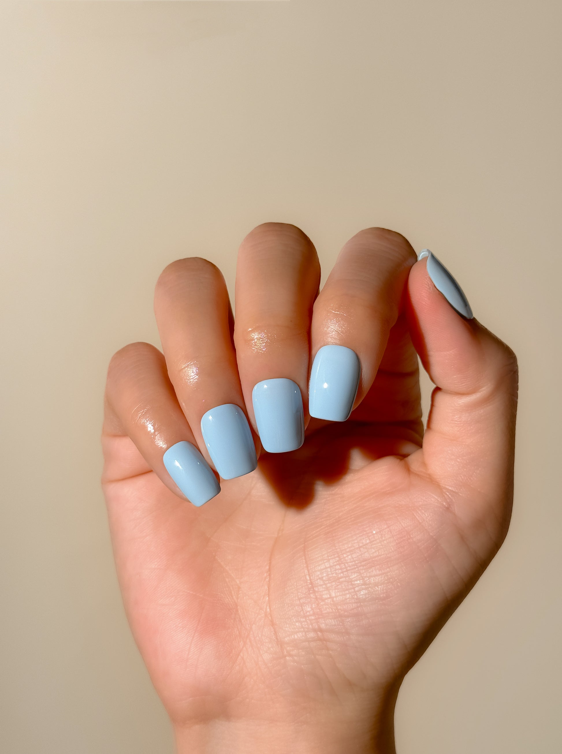 Bluebell handmade press-on nails on one hand, featuring a smooth baby blue shade, high-gloss finish and short square shape.
