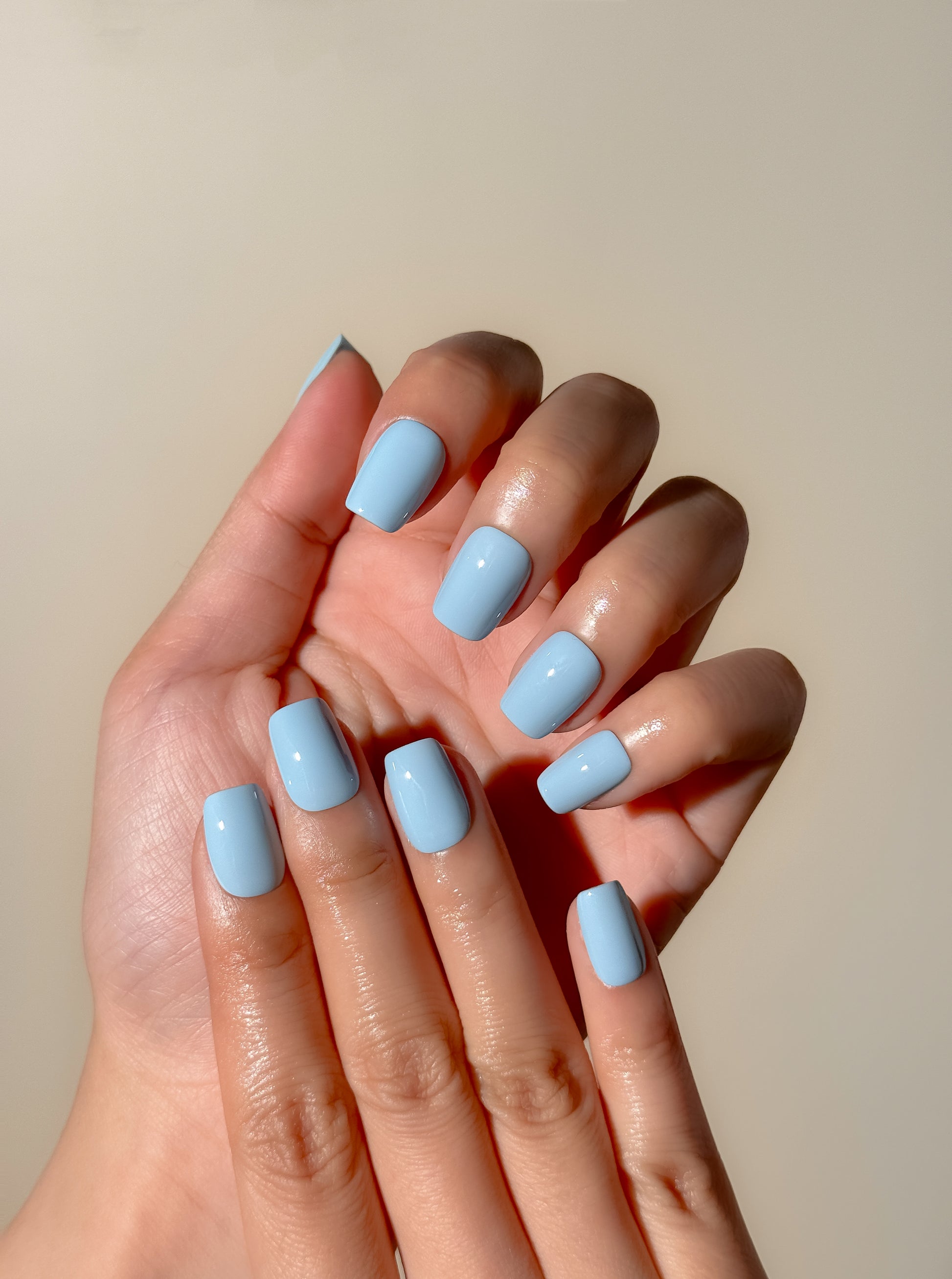 Bluebell press-on nails worn on both hands, showing a clean pastel blue manicure with a glossy short square finish.