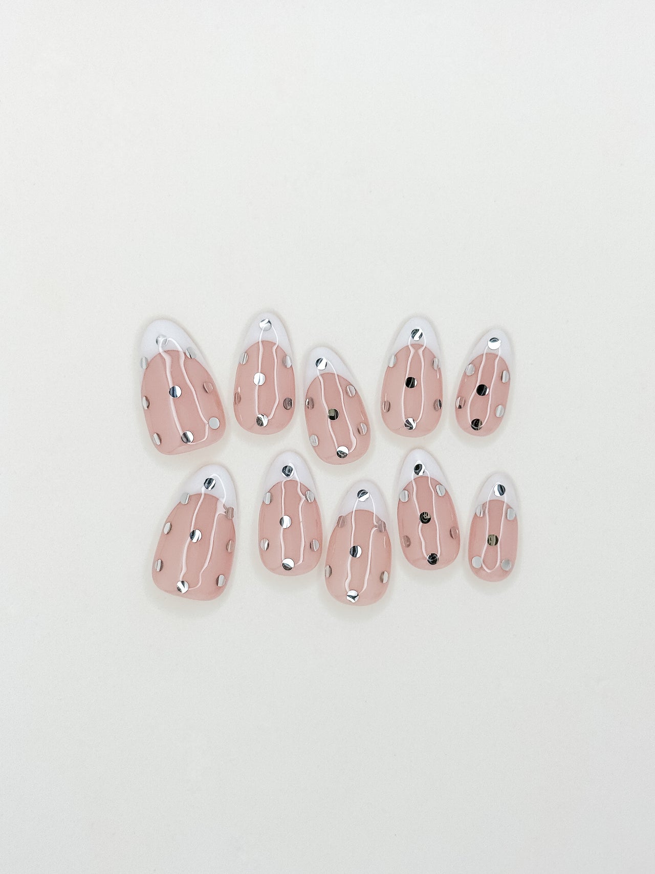 White French tip press-on nails with metallic silver polka dot detailing in a medium almond shape. Handmade reusable false nails inspired by playful French manicures, glossy polka dot nail art and elevated party-ready nail designs.