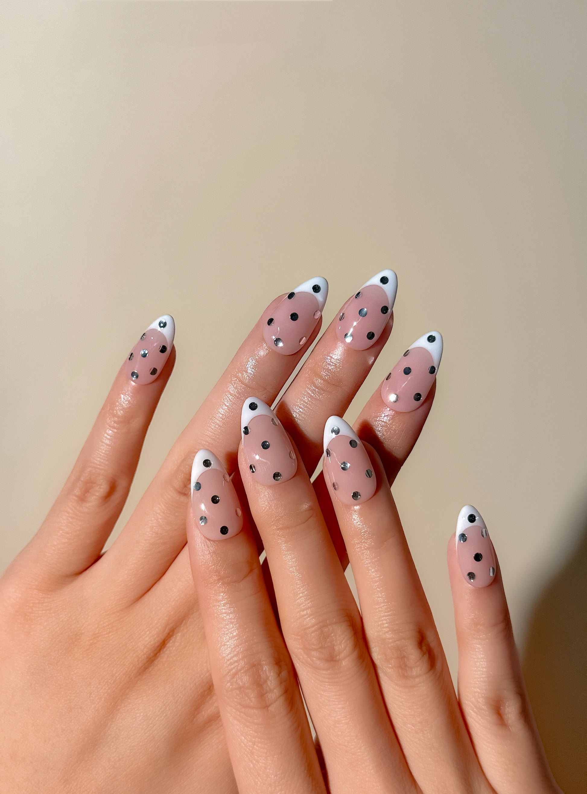 White French tip press-on nails with metallic silver polka dot detailing in a medium almond shape. Handmade reusable false nails inspired by playful French manicures, glossy polka dot nail art and elevated party-ready nail designs.