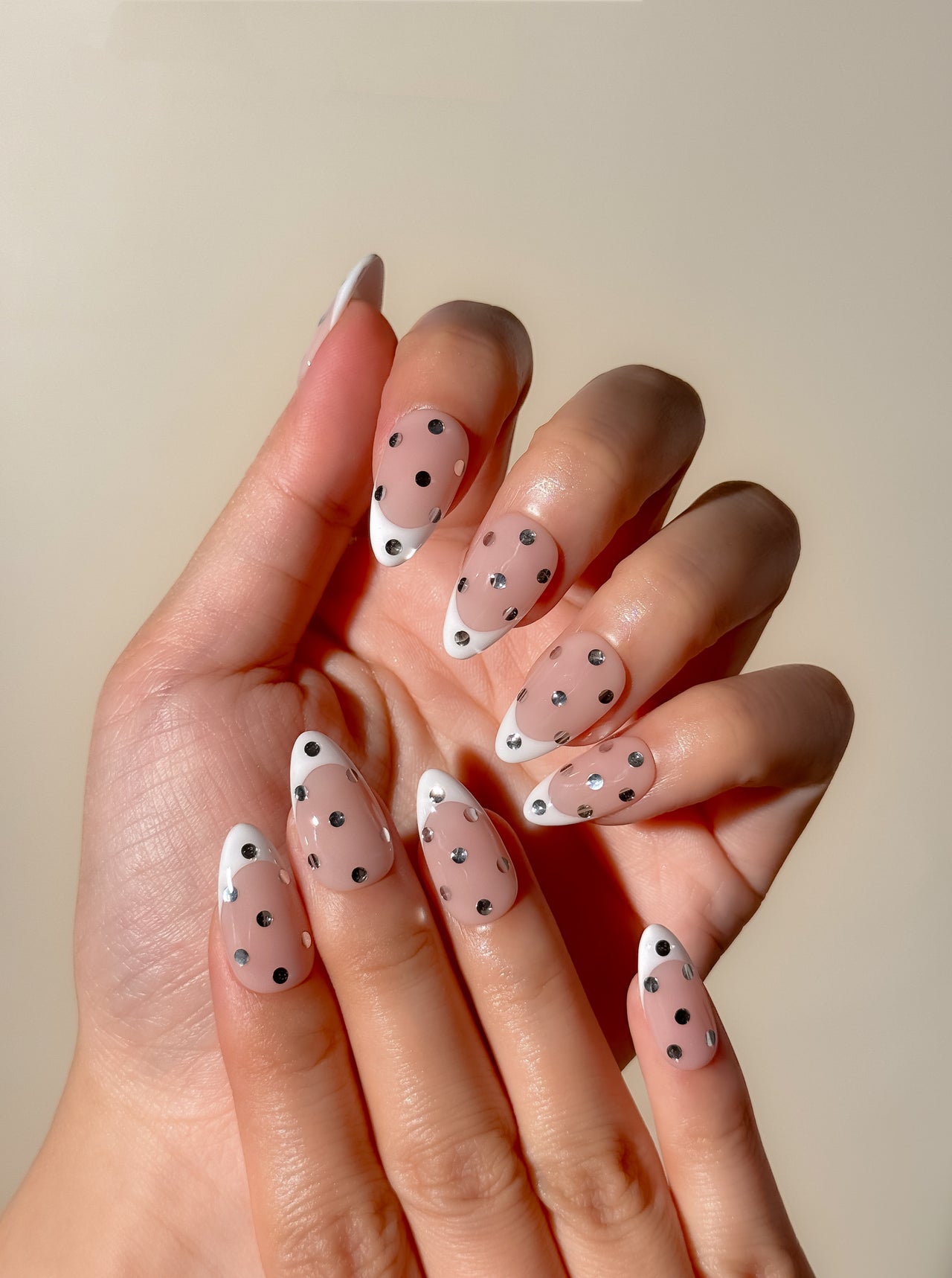 White French tip press-on nails with metallic silver polka dot detailing in a medium almond shape. Handmade reusable false nails inspired by playful French manicures, glossy polka dot nail art and elevated party-ready nail designs.