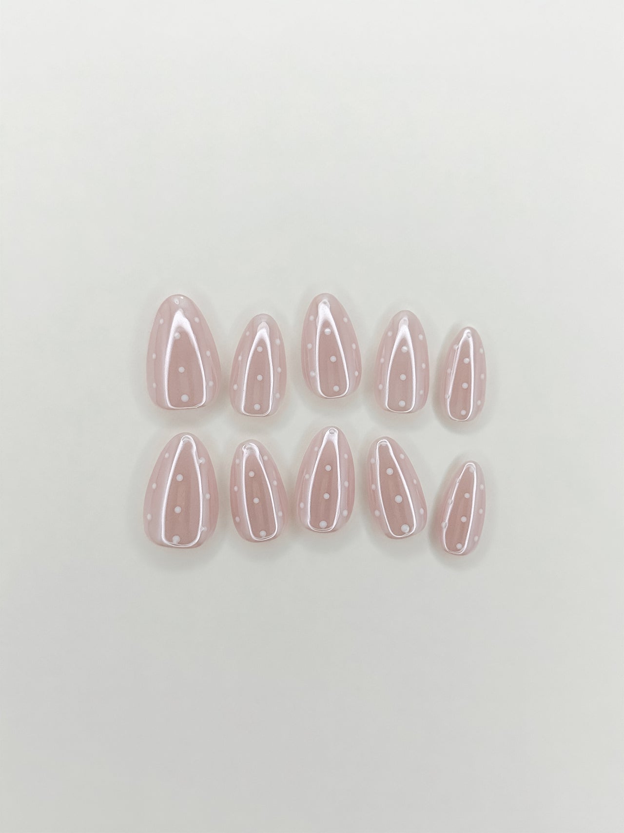 Dottie Glaze handmade gel press-on nails with sheer pink glazed base, white polka dots and glossy short almond shape