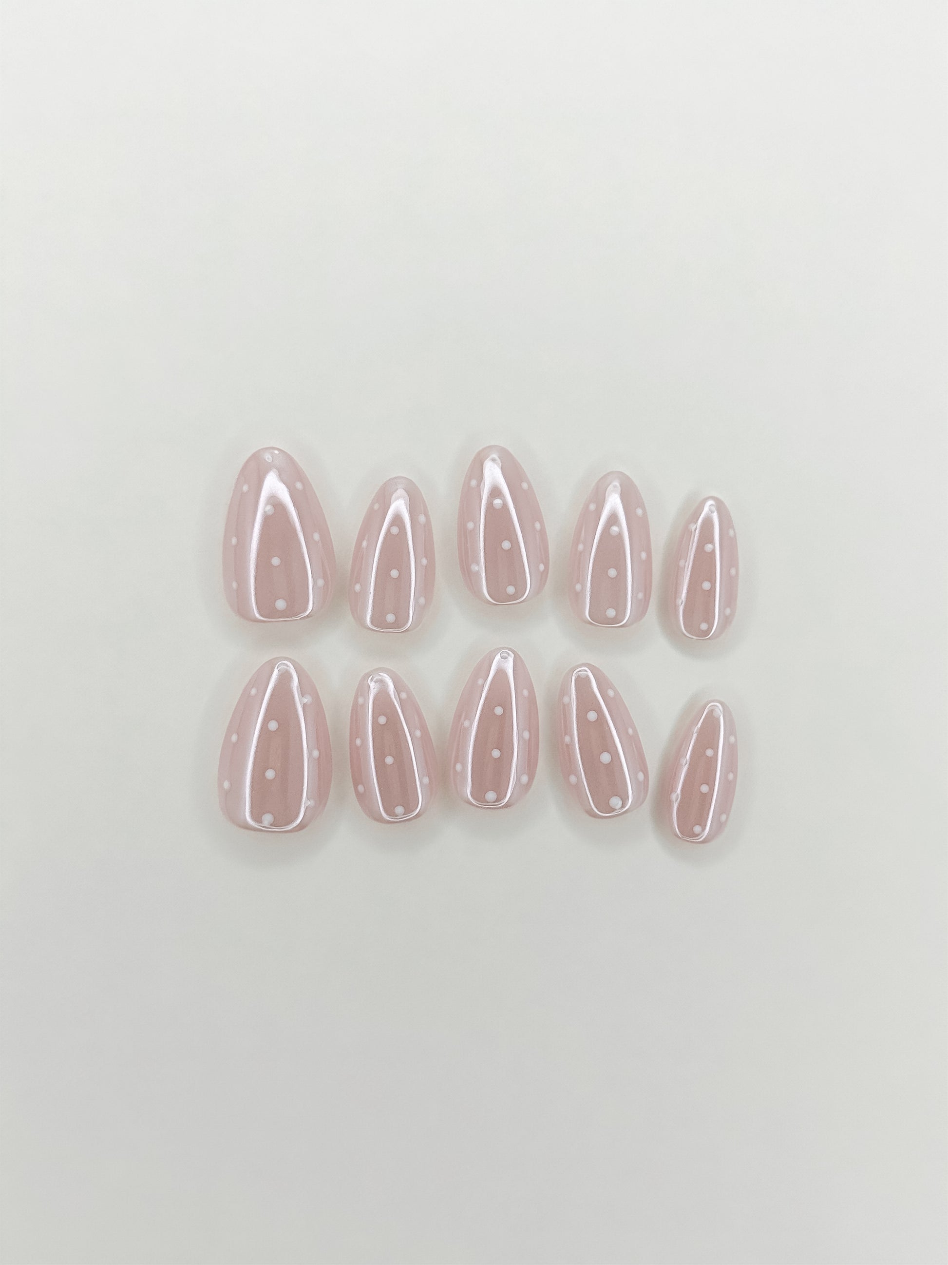 Dottie Glaze handmade gel press-on nails with sheer pink glazed base, white polka dots and glossy short almond shape