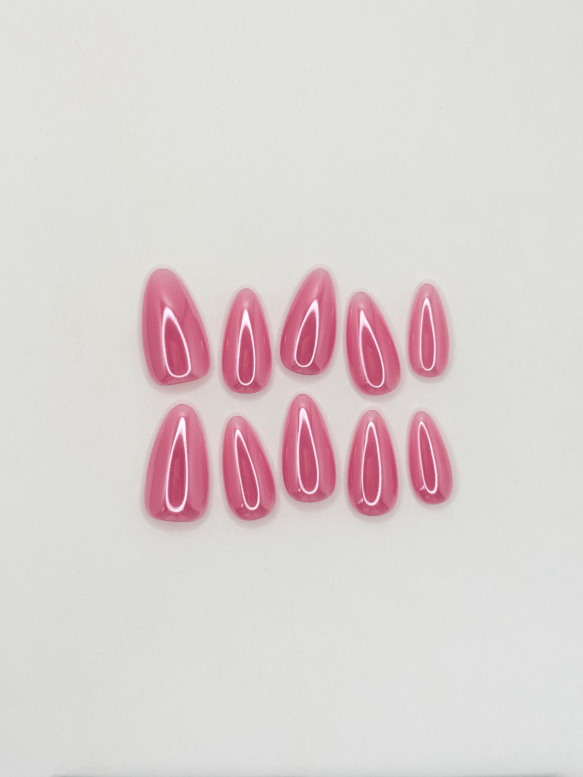 Glossy guava pink glazed press-on nails in a medium almond shape with a translucent tropical finish. Handmade reusable false nails inspired by juicy pink nails, glazed summer manicures and clean girl glossy nail trends.