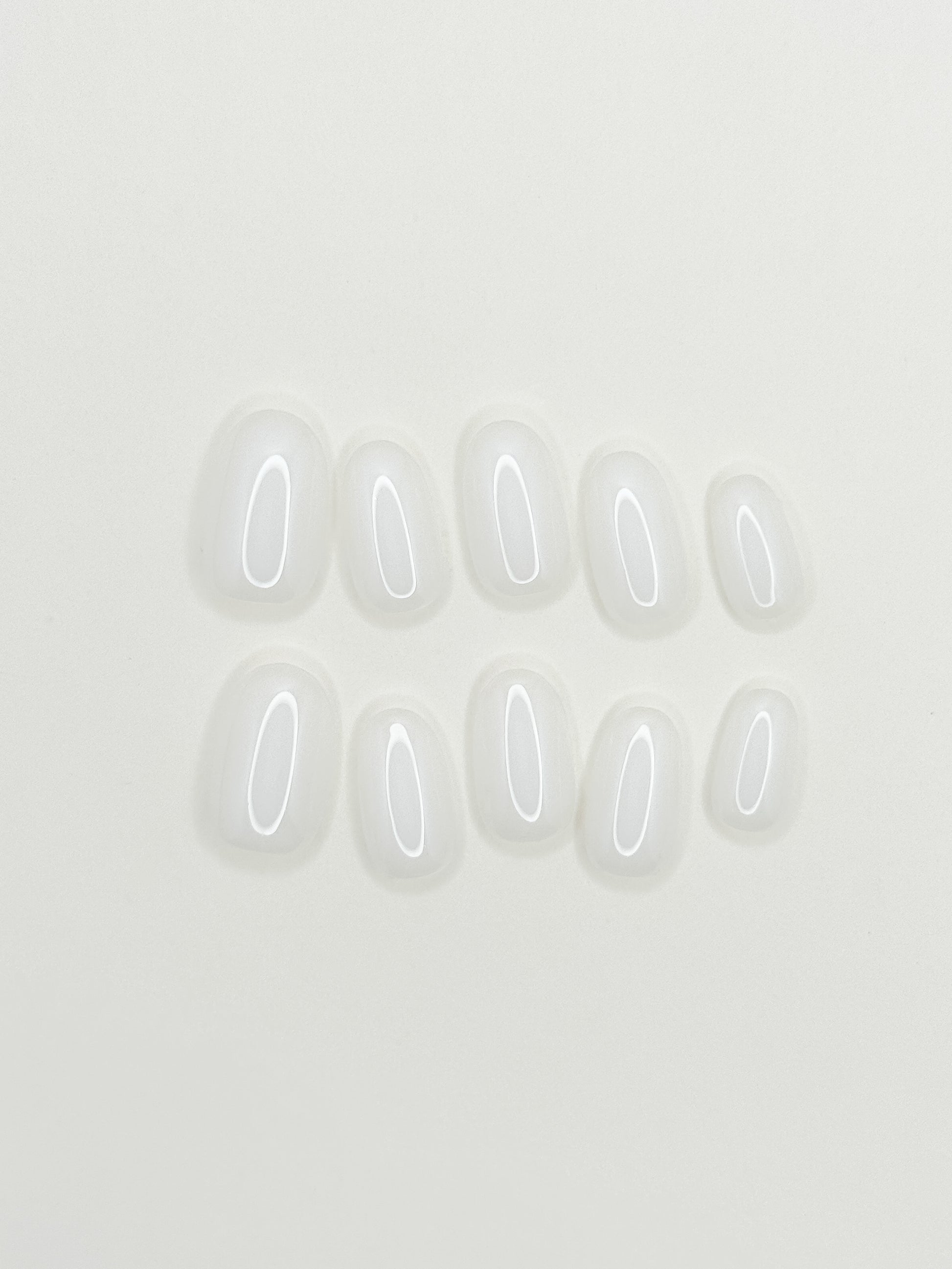 Glossy creamy ivory press-on nails in a short oval shape with a soft gel-like milky finish. Handmade reusable false nails inspired by clean girl nails, vanilla cream manicures and minimal everyday elegance.
