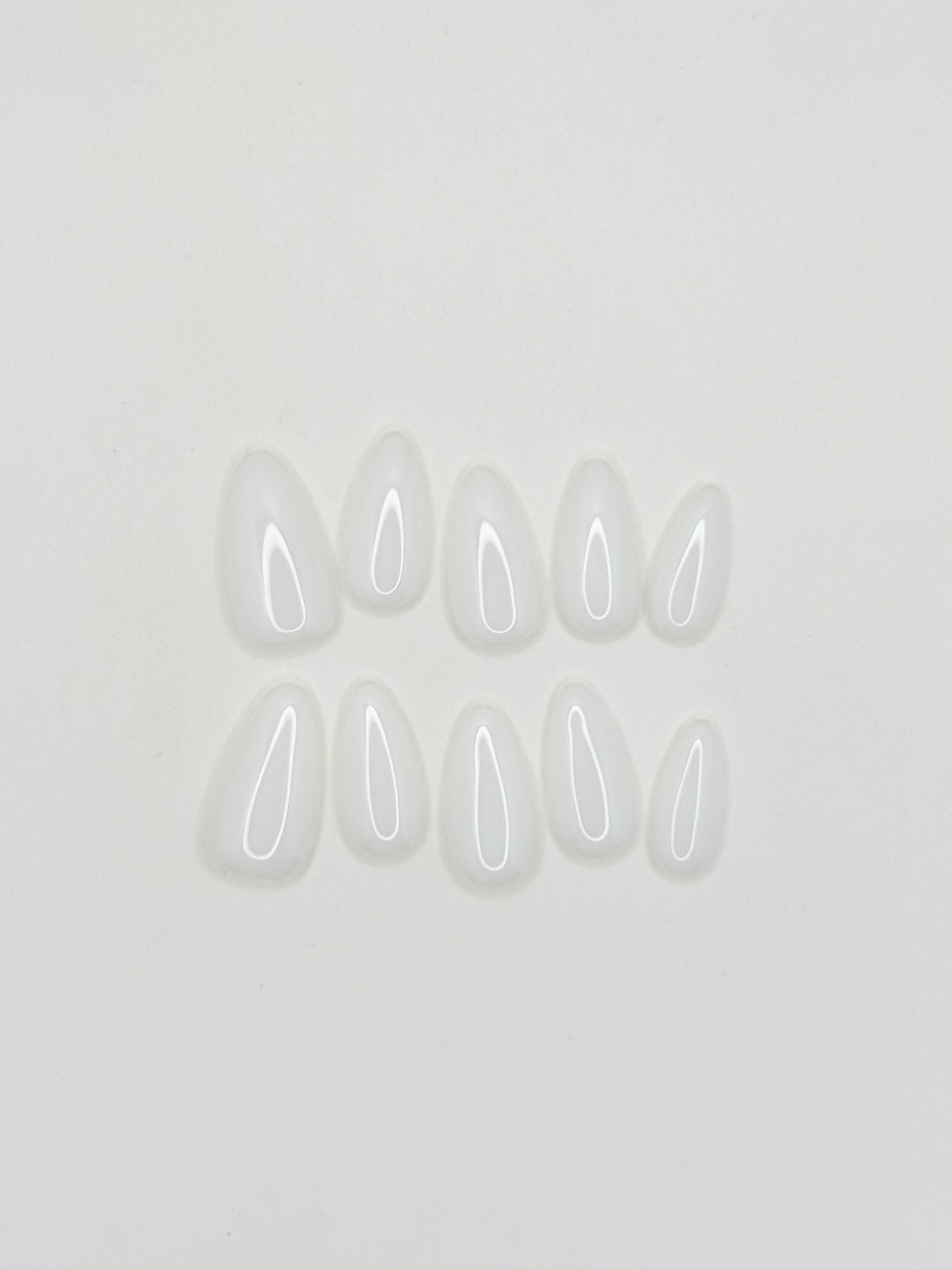 Glossy creamy ivory press-on nails in a medium almond shape with a smooth gel-like milky finish. Handmade reusable false nails inspired by luxury neutral manicures, vanilla-toned nails and elevated clean girl beauty.