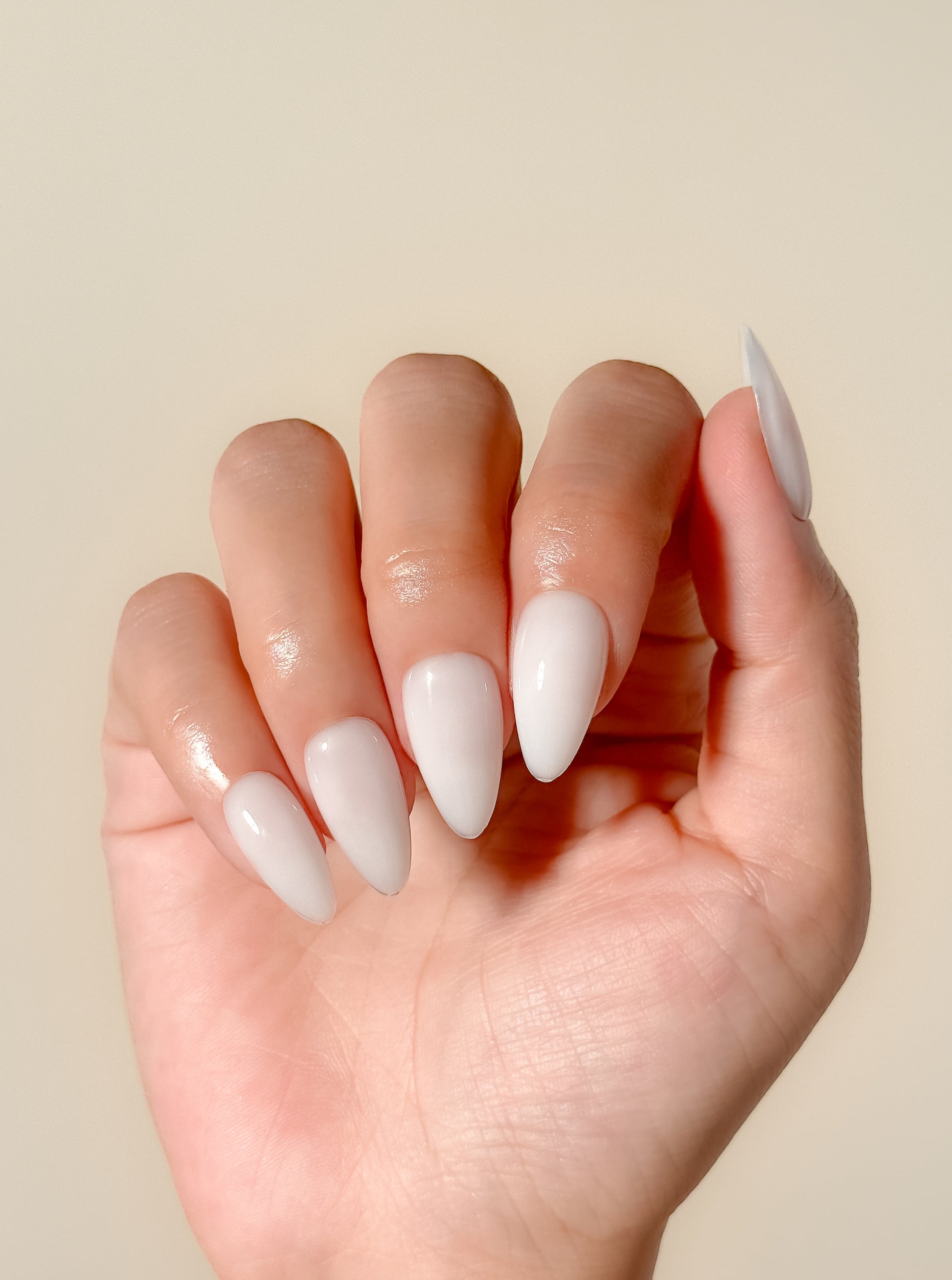 Glossy creamy ivory press-on nails in a medium almond shape with a smooth gel-like milky finish. Handmade reusable false nails inspired by luxury neutral manicures, vanilla-toned nails and elevated clean girl beauty.