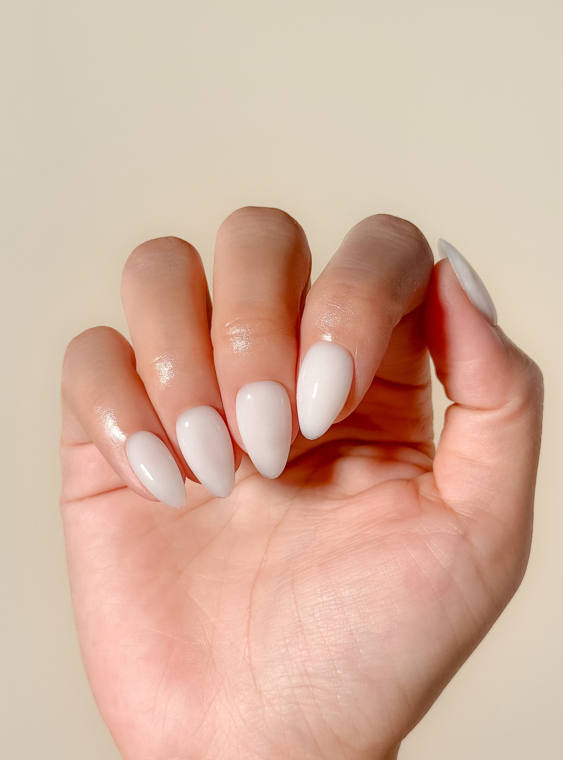 Glossy creamy ivory press-on nails in a short almond shape with a smooth gel-like milky finish. Handmade reusable false nails inspired by vanilla cream nails, clean girl manicures and minimalist neutral nail trends.