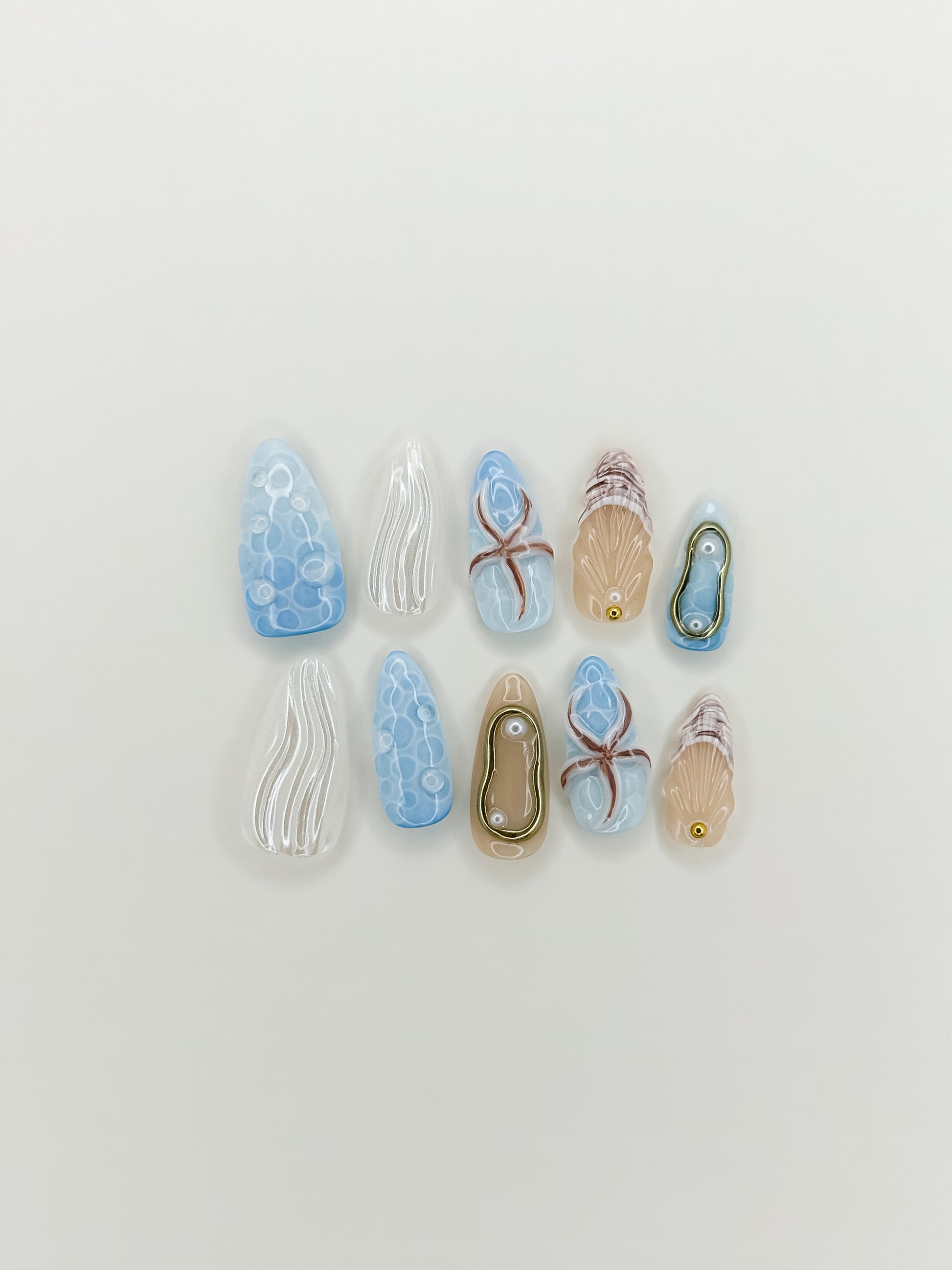 Laguna handmade gel press-on nails with ocean-inspired blue 3D nail art, shell details, pearl accents and gold charms in medium almond shape