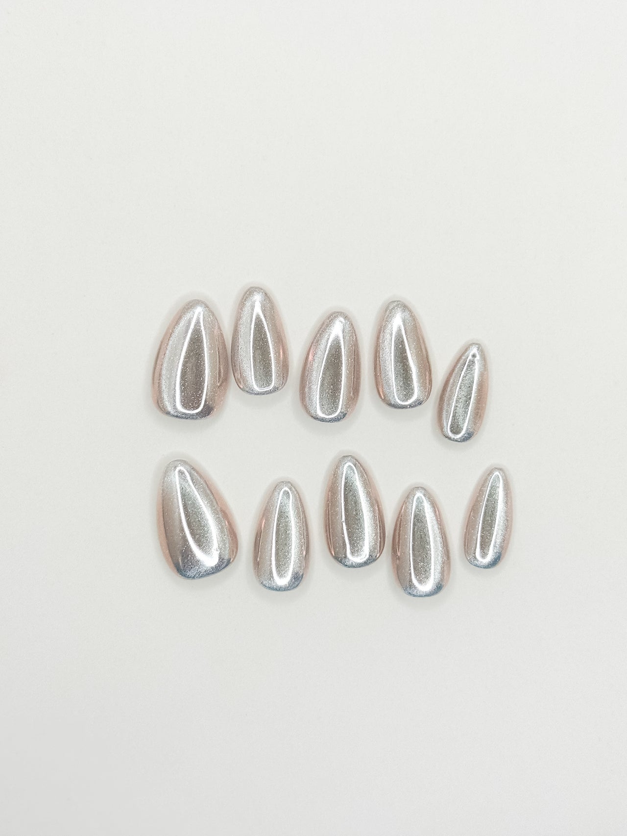 Silver chrome cat-eye press-on nails in a glossy short almond shape with reflective metallic detailing. Handmade reusable false nails inspired by liquid metal nails, futuristic chrome manicures and magnetic cat-eye nail trends.