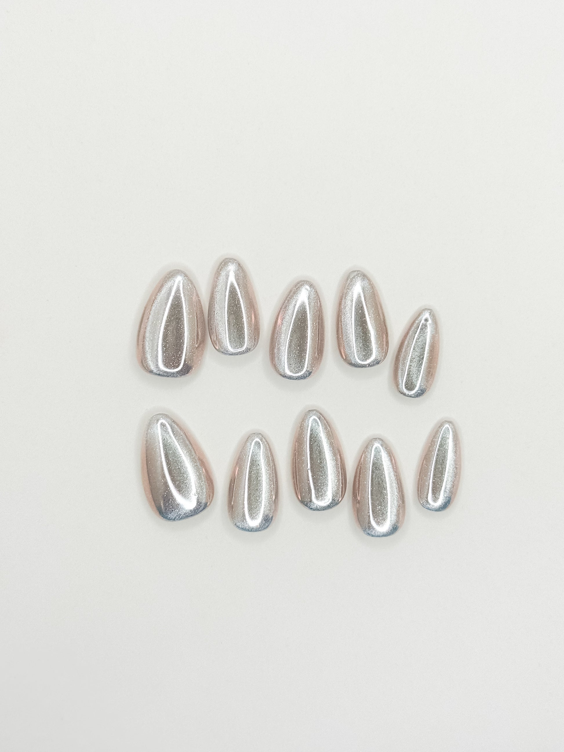 Silver chrome cat-eye press-on nails in a glossy short almond shape with reflective metallic detailing. Handmade reusable false nails inspired by liquid metal nails, futuristic chrome manicures and magnetic cat-eye nail trends.