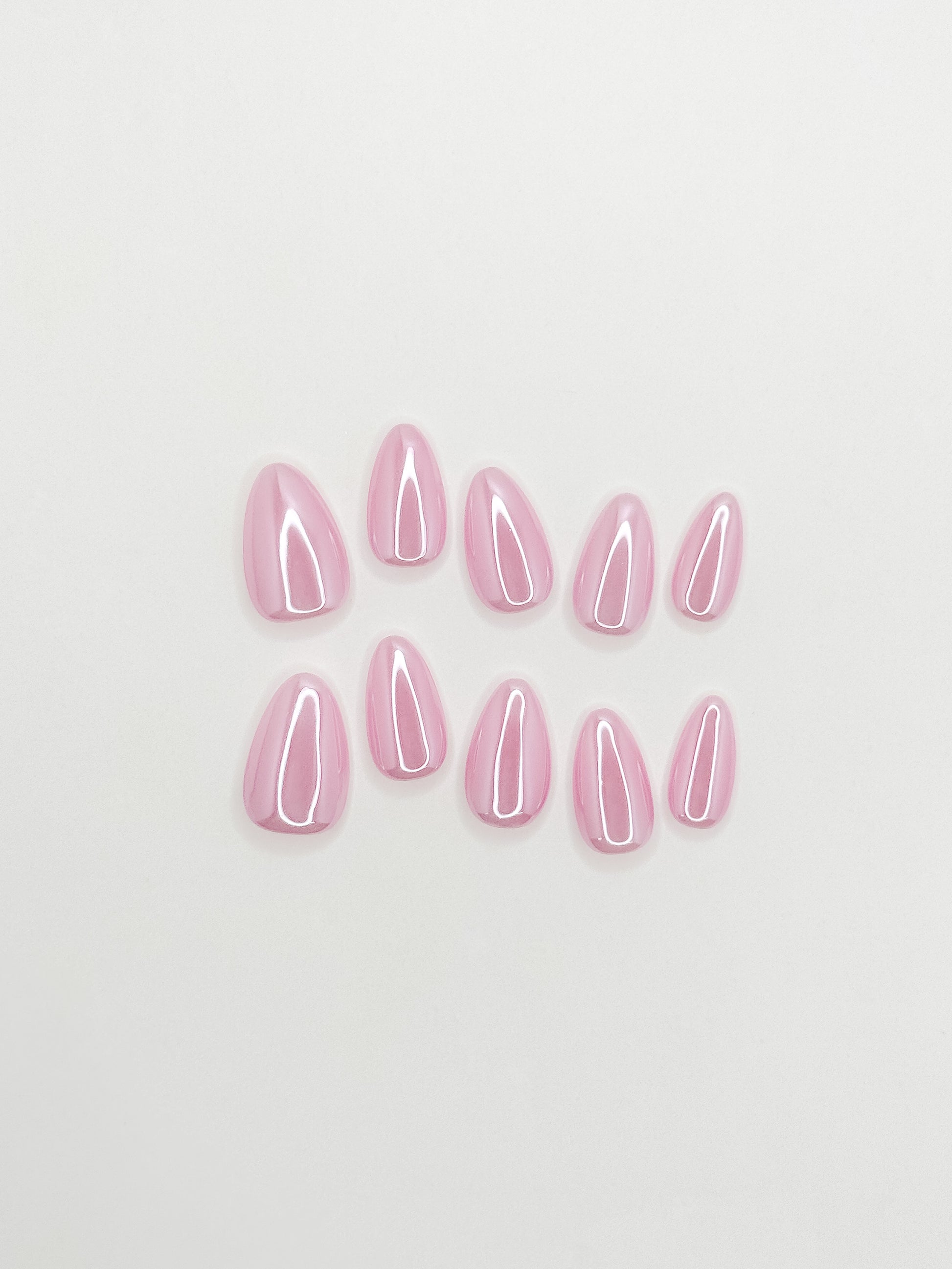 Glossy pink glazed press-on nails in a short almond shape with a translucent candy pink finish. Handmade reusable false nails inspired by glazed donut nails, clean girl manicures and soft glossy pink nail trends.