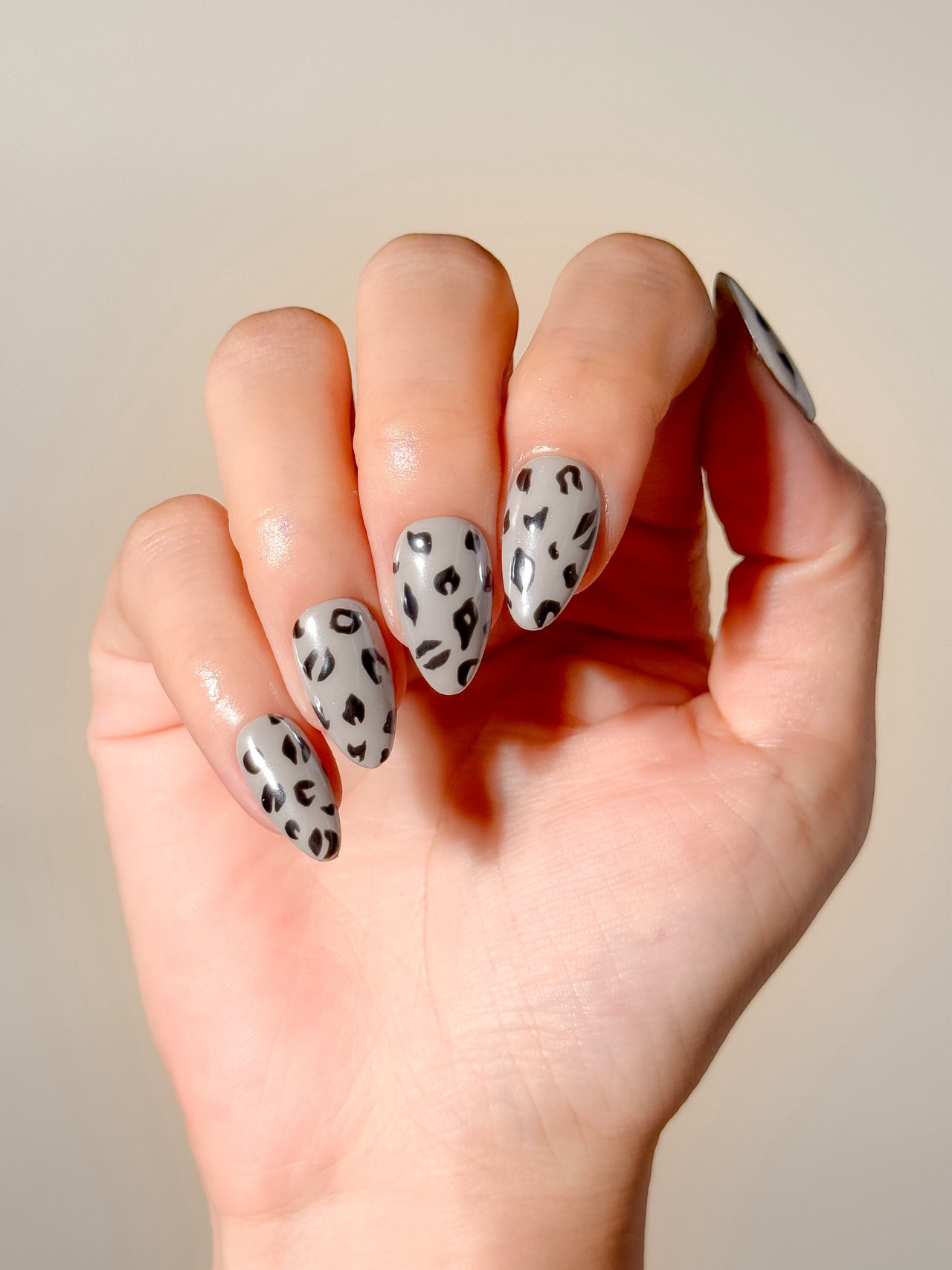 Roadie handmade short almond press-on nails arranged on white, featuring reflective silver chrome and black leopard-print spots.
