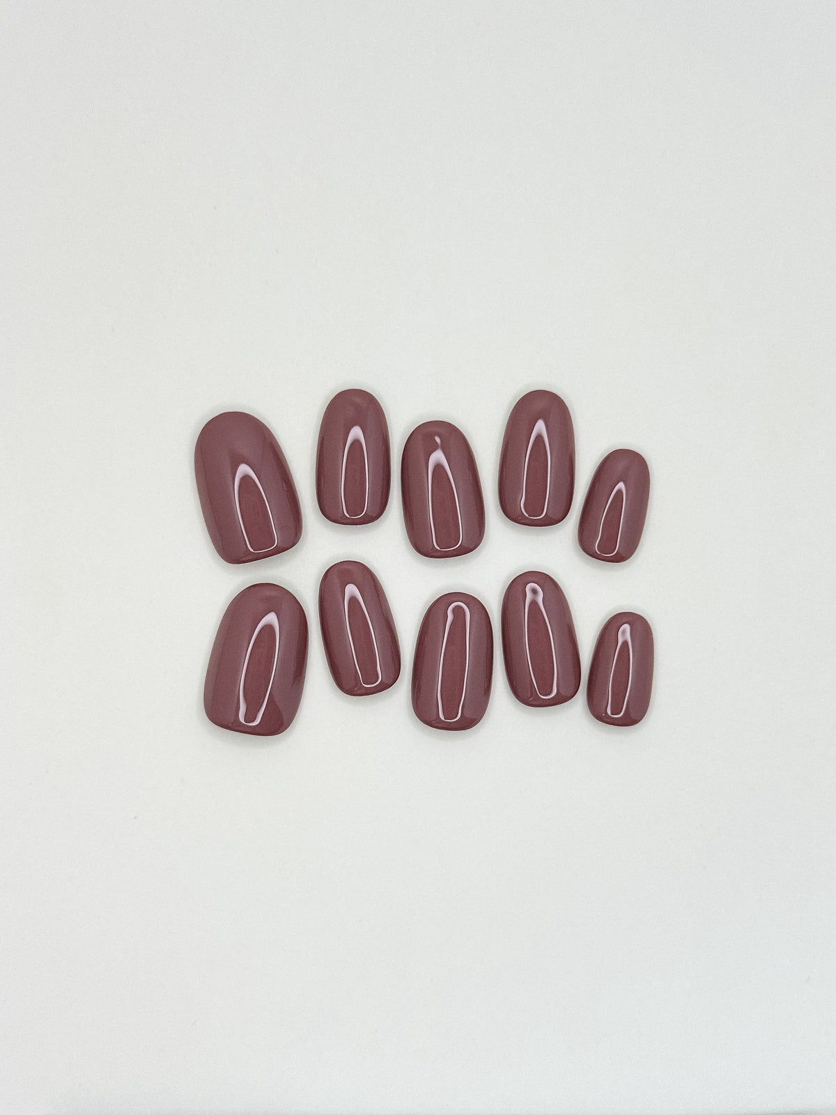 Velvet Blush short oval press-on nail set laid flat, featuring a glossy solid mauve-taupe colour.