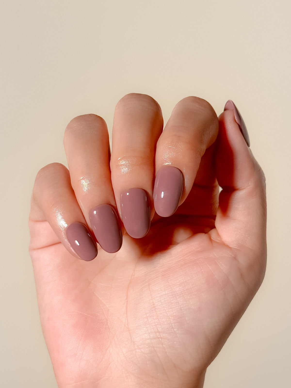Velvet Blush short oval press-on nail set laid flat, featuring a glossy solid mauve-taupe colour.