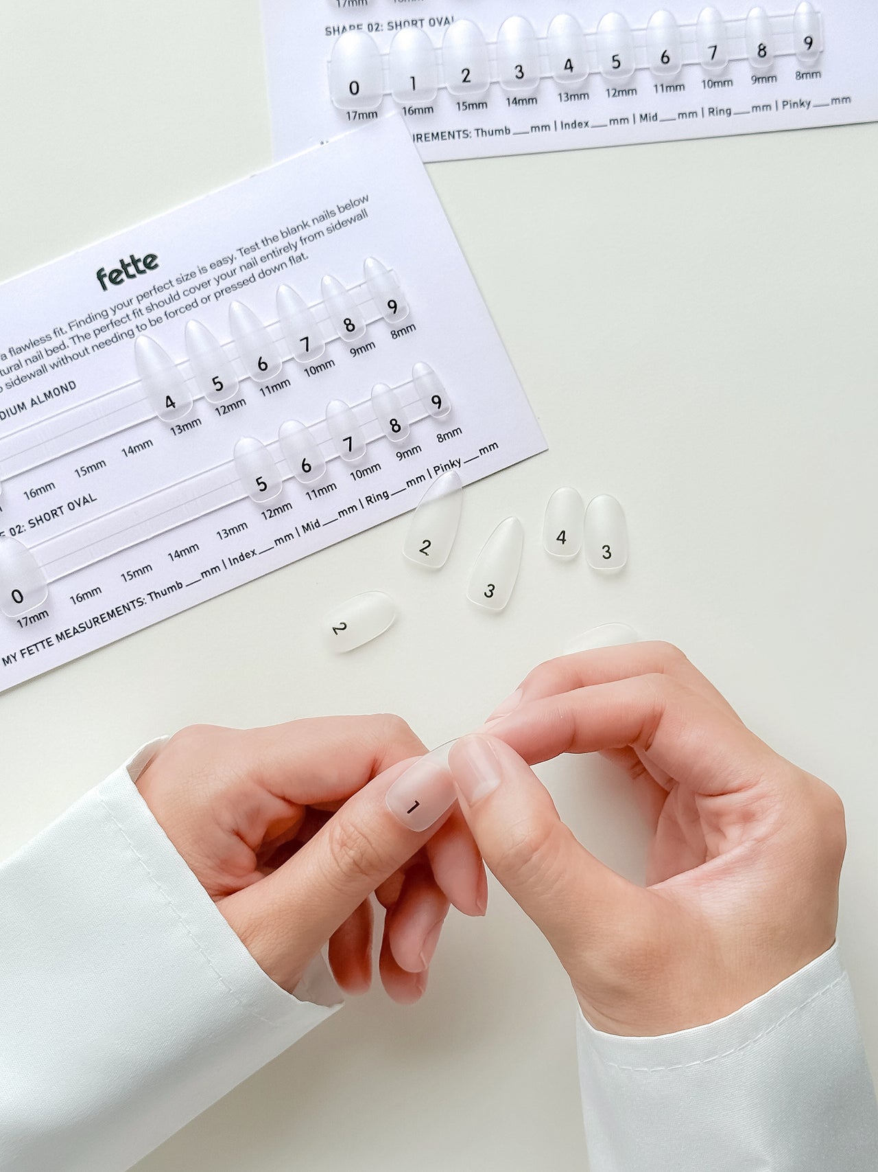 Fette press-on nail sizing kit card displaying medium almond and short oval nail sizes from 0 to 9 for accurate reusable false nail fitting.