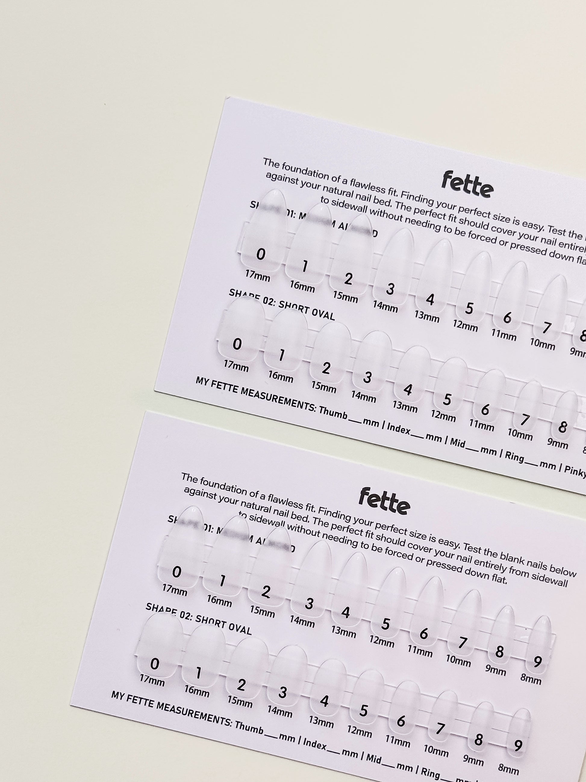 Person holding Fette nail sizing card with labelled press-on nail sizes for finding the perfect custom fit at home.