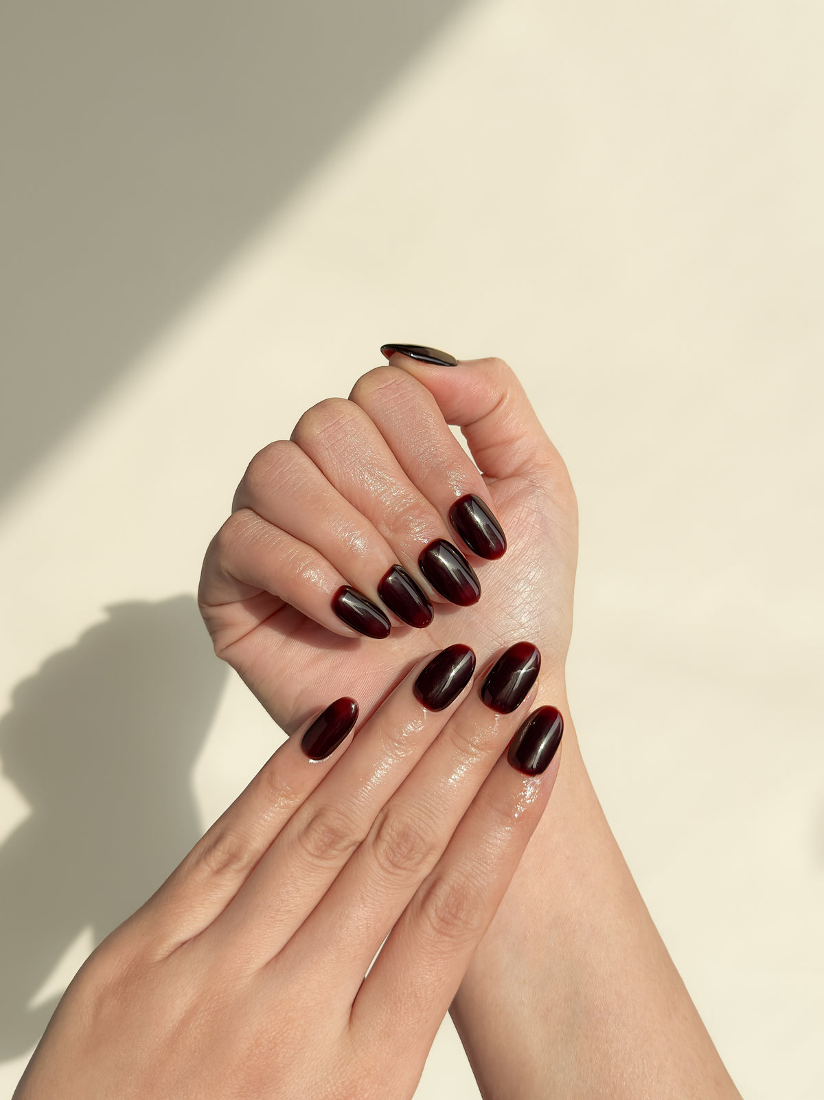 Close-up of a hand wearing Coffee Break espresso brown short oval press-on nails with a high-gloss finish.