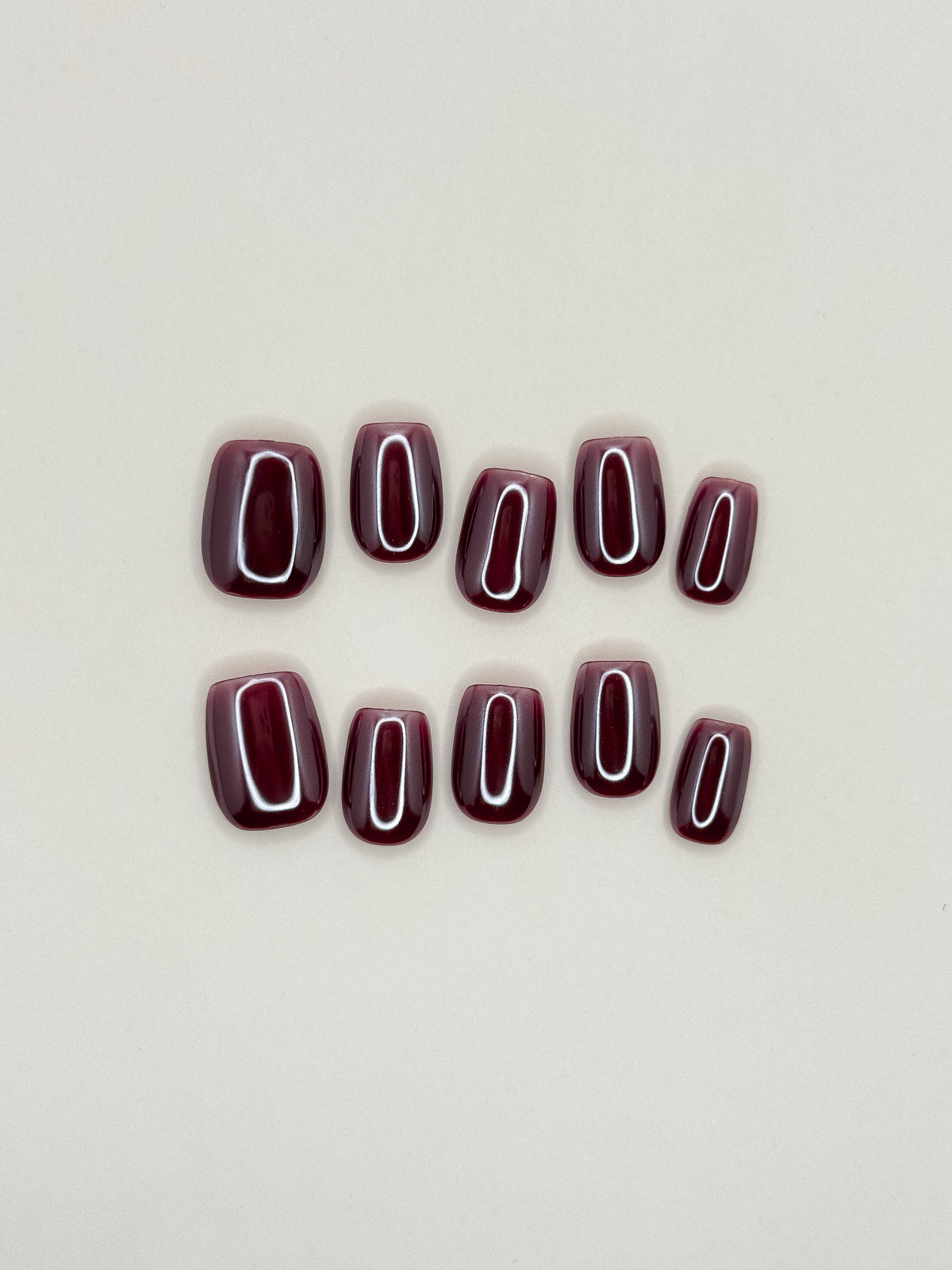 Deadline glazed brick-red wine short square press-on nails arranged as a glossy reusable set on a white background.