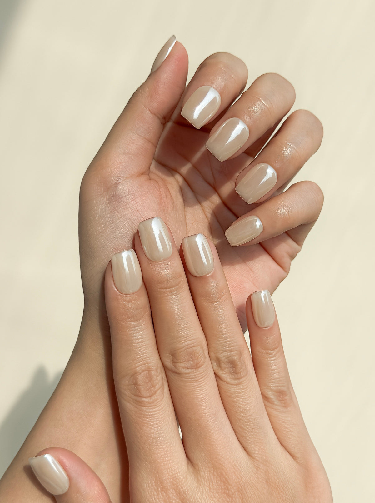 Close-up of a hand wearing Early Rise milky cream short square press-on nails with a luminous glazed finish.