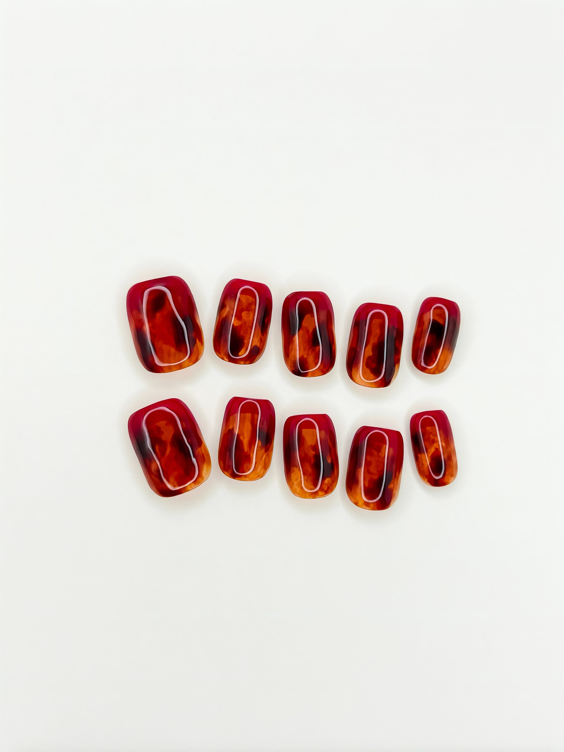 Heatwave press on nails: ten short square-shaped red and amber tortoiseshell resin nails arranged in two rows on a plain white background.