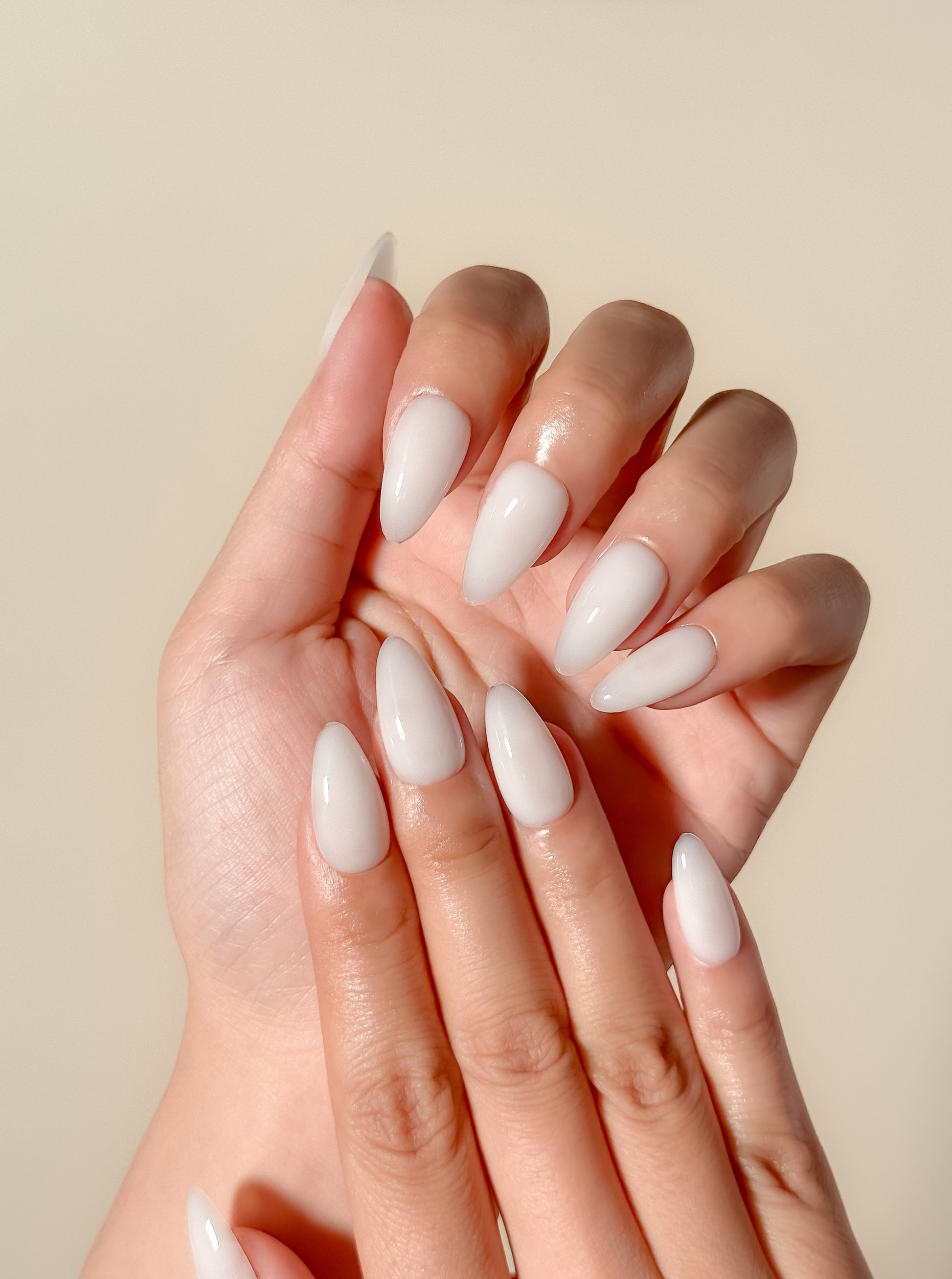 Glossy creamy ivory press-on nails in a medium almond shape with a smooth gel-like milky finish. Handmade reusable false nails inspired by luxury neutral manicures, vanilla-toned nails and elevated clean girl beauty.