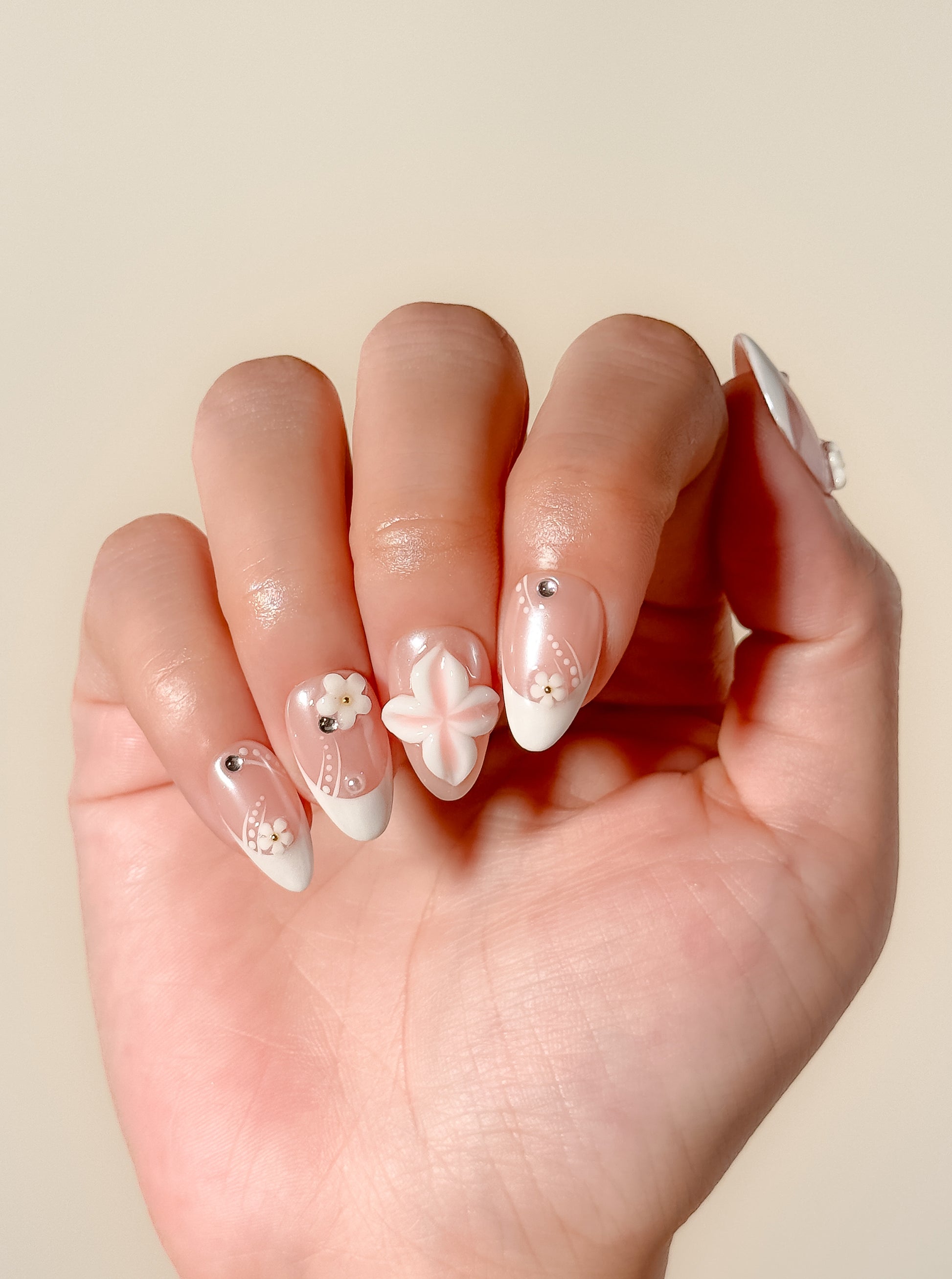 Last Call white French-tip press-on nails worn on one hand, featuring sculpted 3D flowers and delicate silver details.