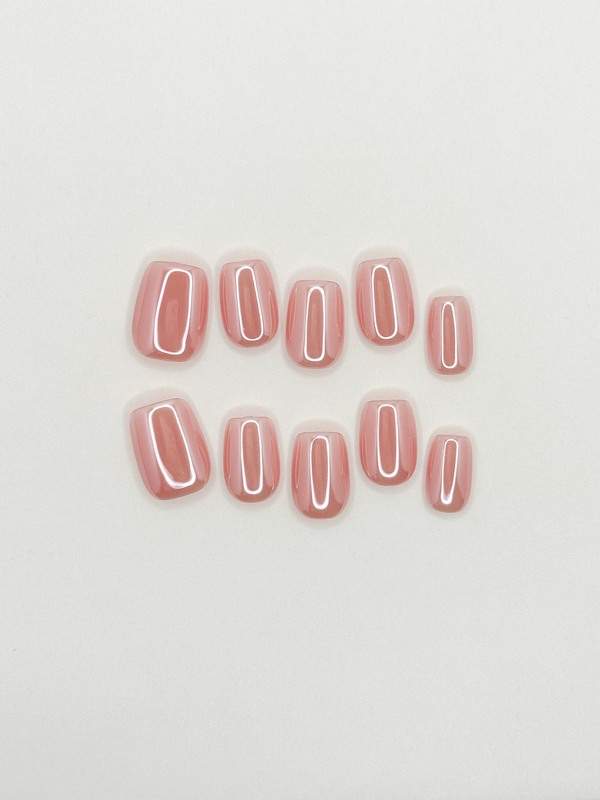 Morning Commute peachy pink glazed short square press-on nails arranged as a luminous reusable set on a white background.