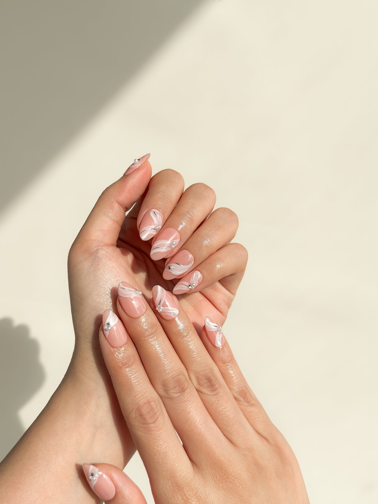One More Night short almond press-on nails arranged on white, with a sheer blush-nude base, raised white ribbon lines and silver crystals.