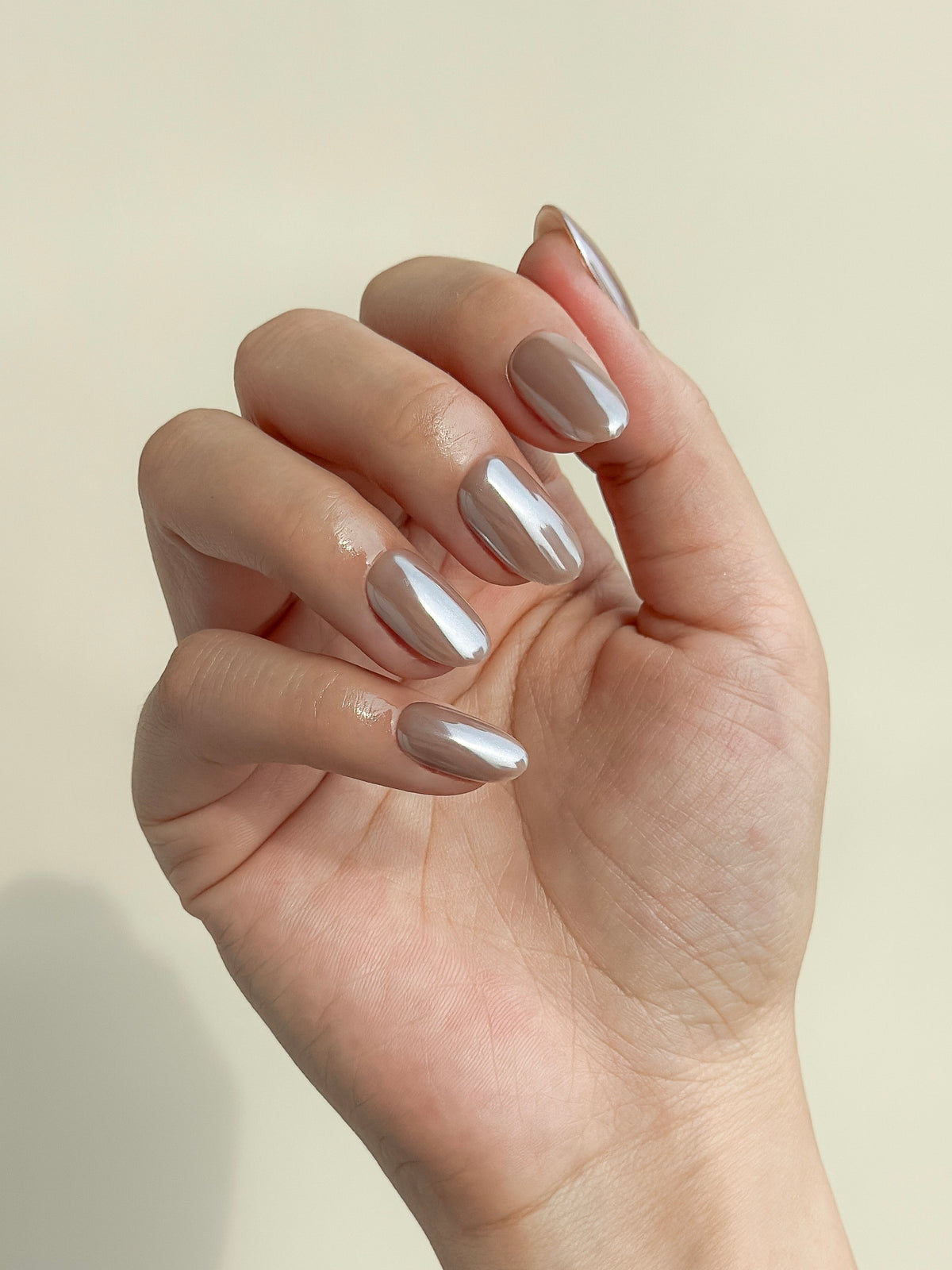 Payday taupe beige nude glazed short oval press-on nails arranged as a luminous reusable set on a white background.