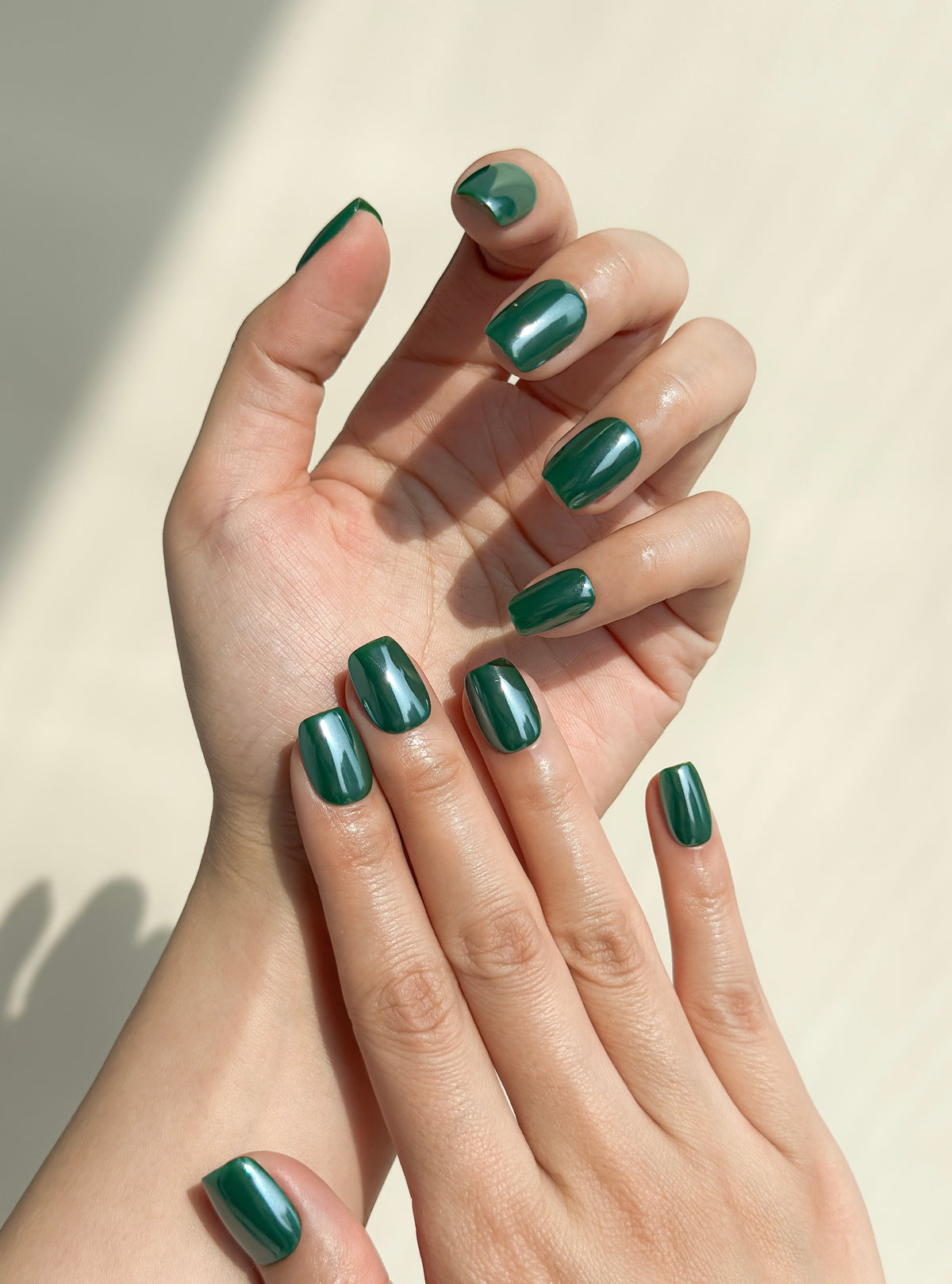 Close-up of a hand wearing Promotion deep forest green short square press-on nails with a high-gloss finish.