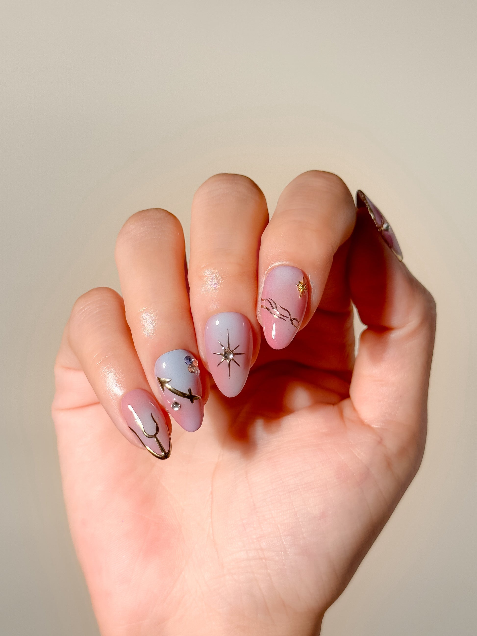 Summer After Dark colourful press-on nails worn on one hand, featuring sunset gradients, metallic stars and delicate crystal accents.