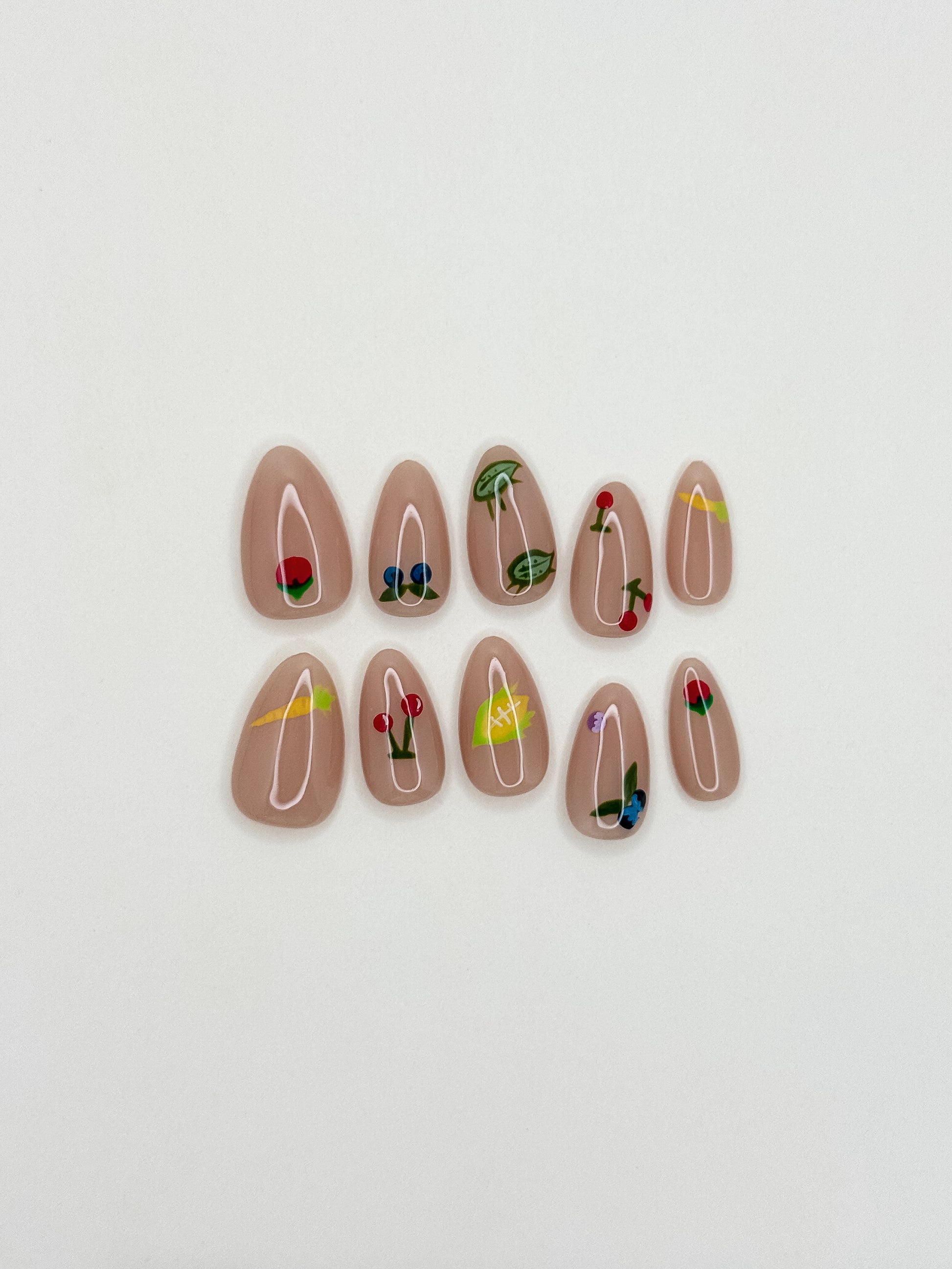 Summer Apron handmade short almond press-on nail set arranged on white, with a glossy nude base and colourful fruit, vegetable, flower and garden-bug illustrations