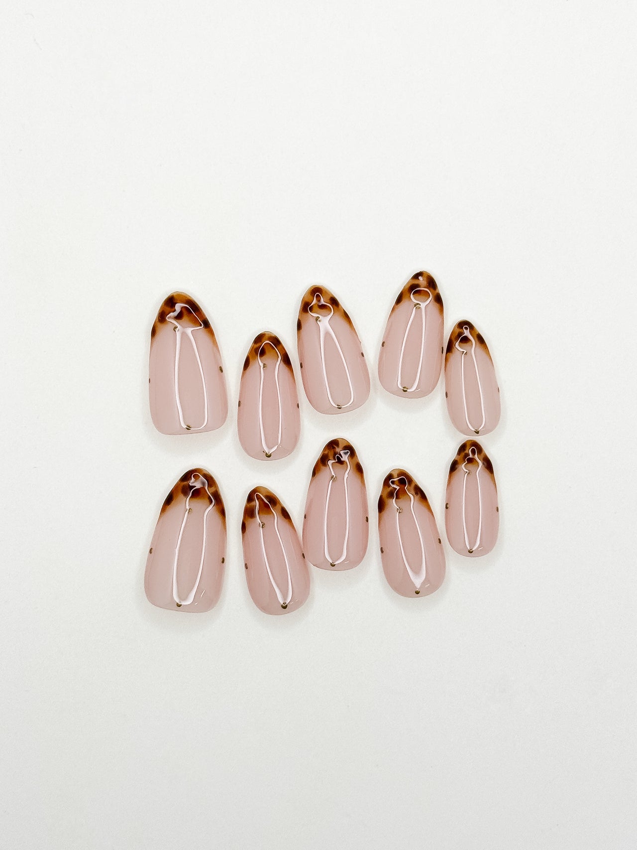 Polka Bloom handmade medium almond press-on nails arranged on white, with black polka-dot French tips and translucent pink 3D flowers