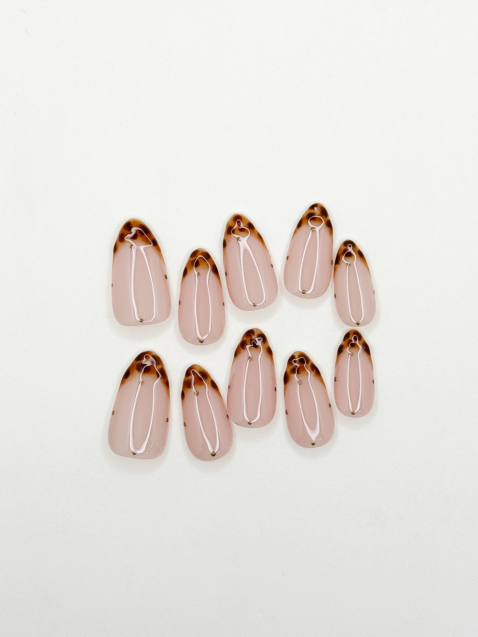Polka Bloom handmade medium almond press-on nails arranged on white, with black polka-dot French tips and translucent pink 3D flowers